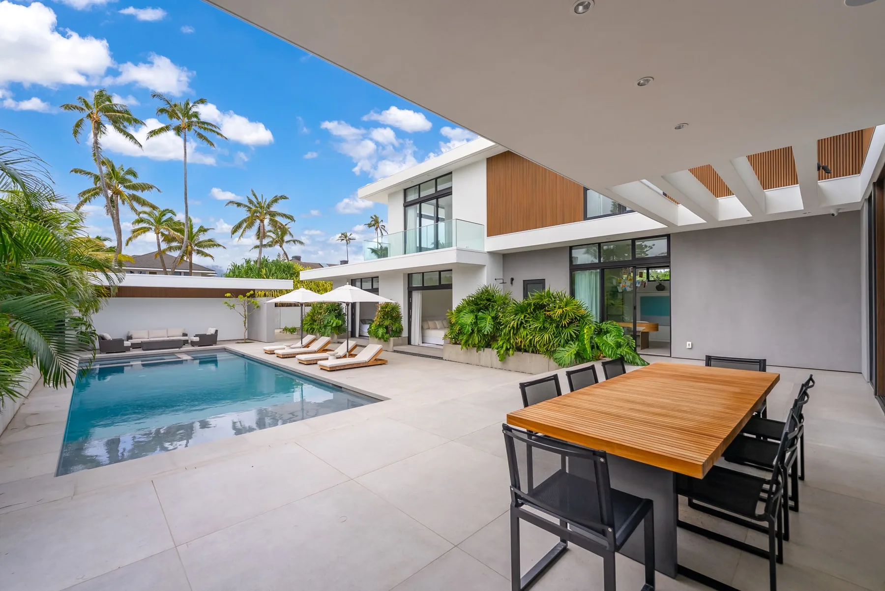 A modern patio with a swimming pool and an outdoor dining table.