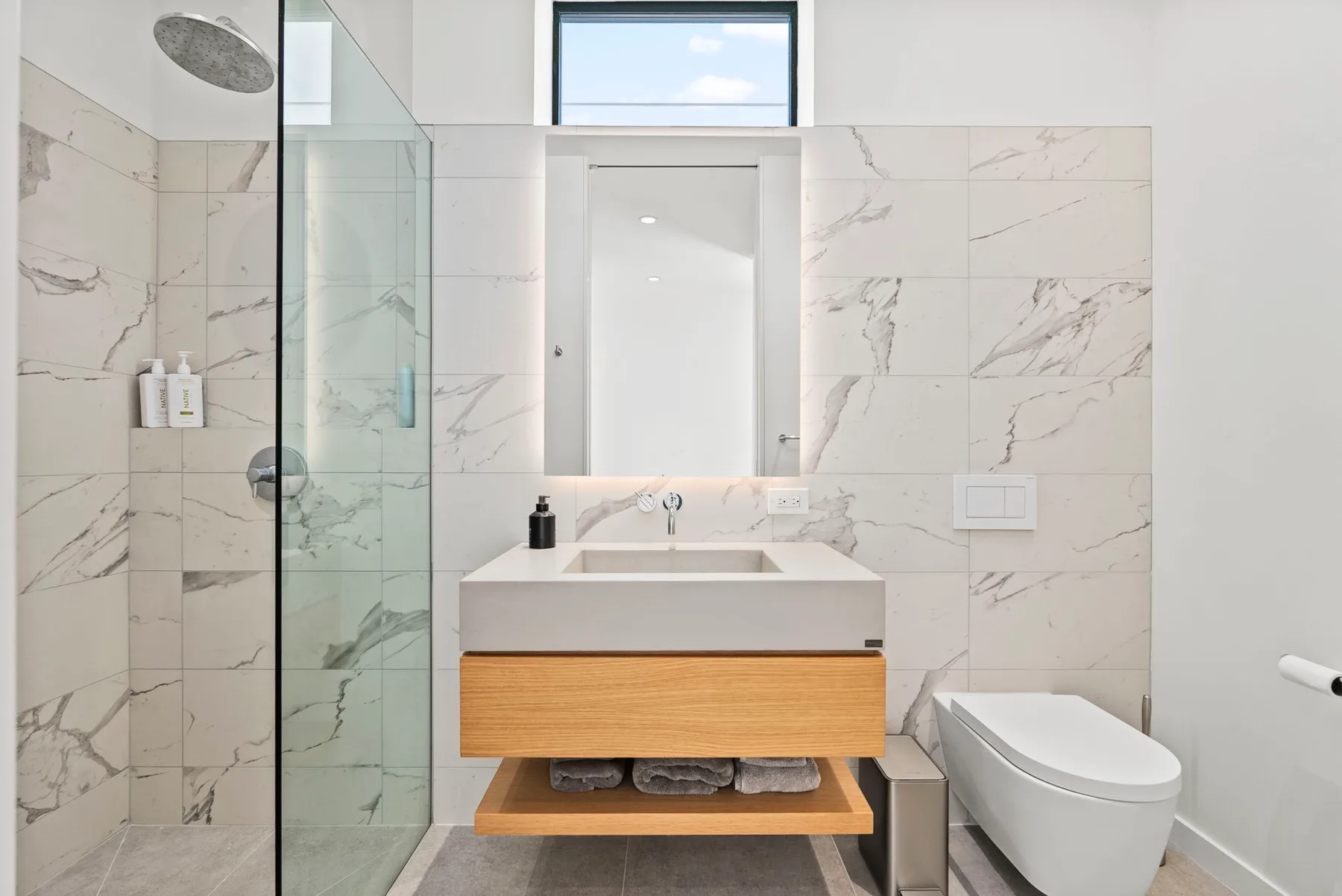 A modern bathroom with a vanity, mirror, and glass shower.