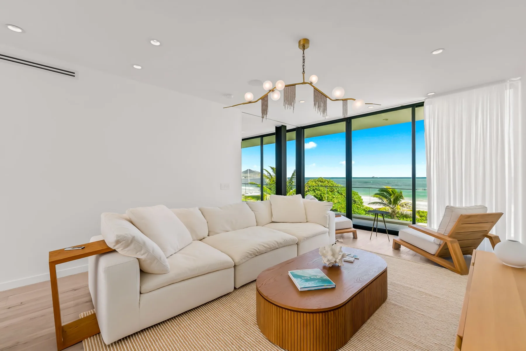 A bright living room opens onto large windows with a view of the sea.