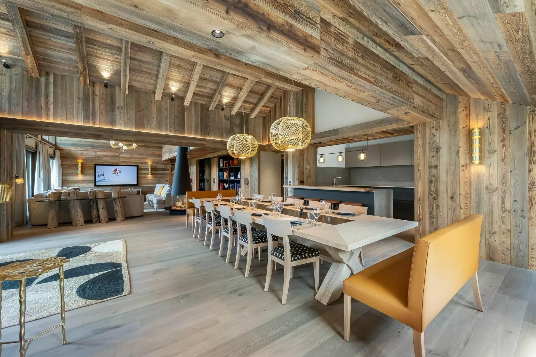 A rustic dining area with a long table, chairs, and pendant lights.