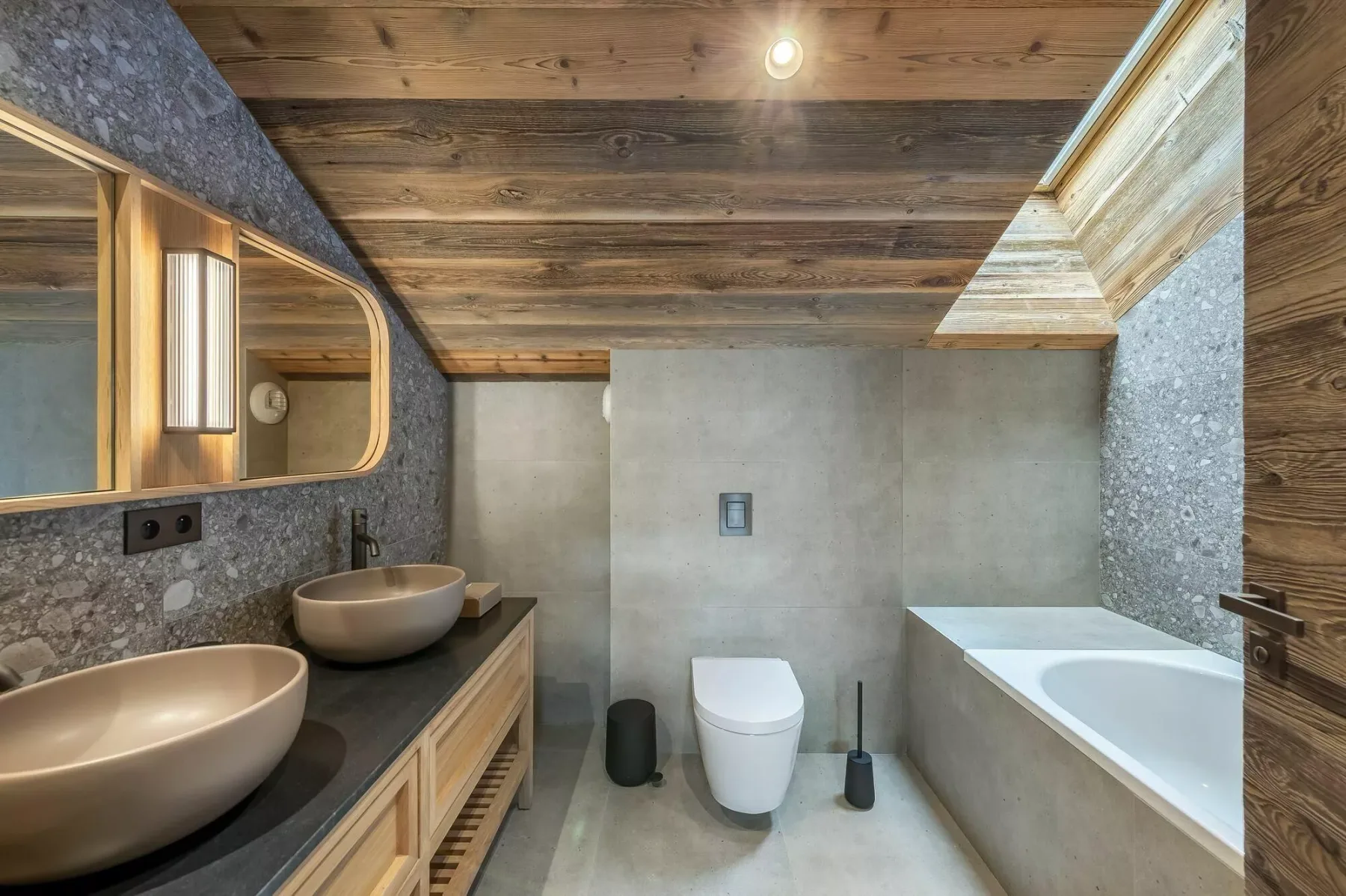 A bathroom with a bathtub, two sinks, and a toilet beneath a wooden ceiling.