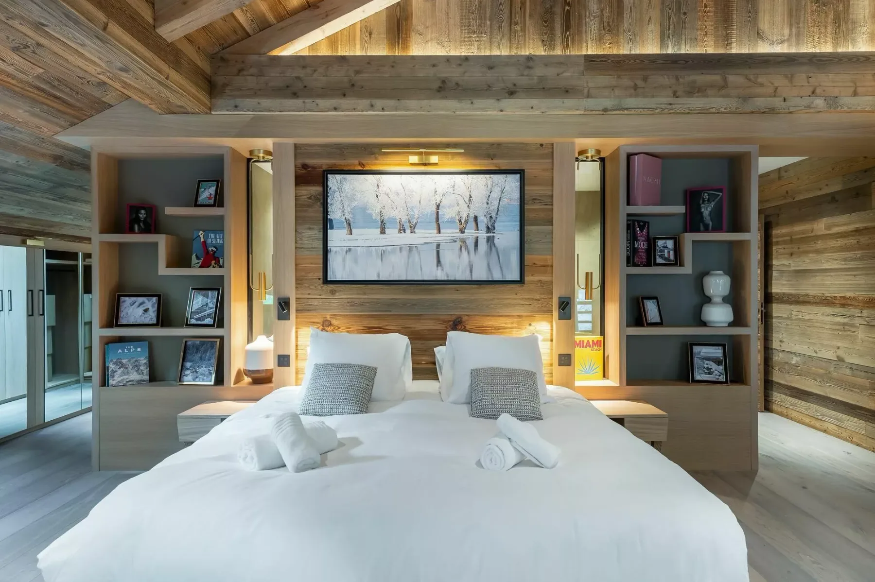 A bedroom with a large bed beneath a framed winter landscape.