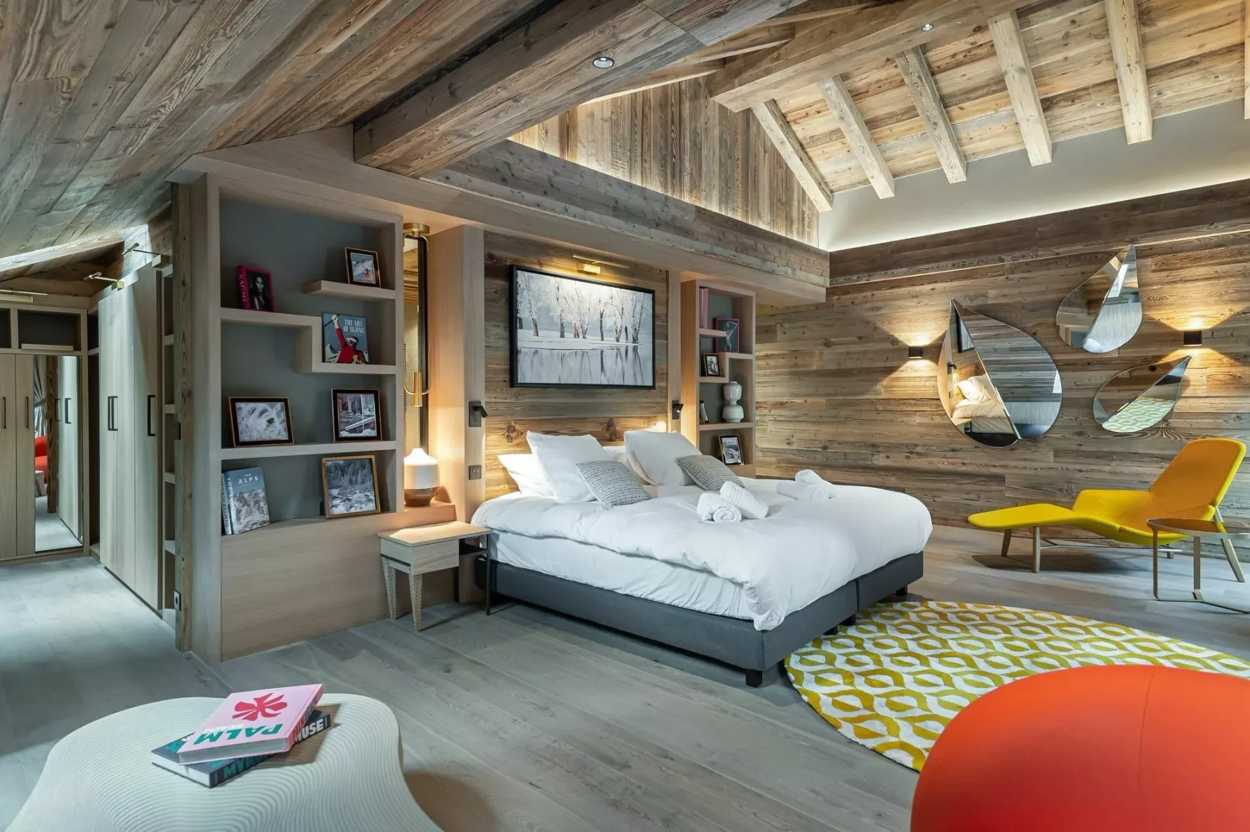 A rustic bedroom with a bed, built-in shelving, and wood-paneled walls.