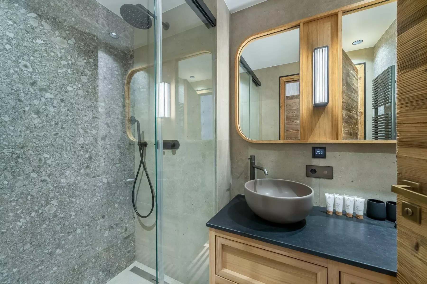 A modern bathroom with a glass shower and a vessel sink on a dark countertop.
