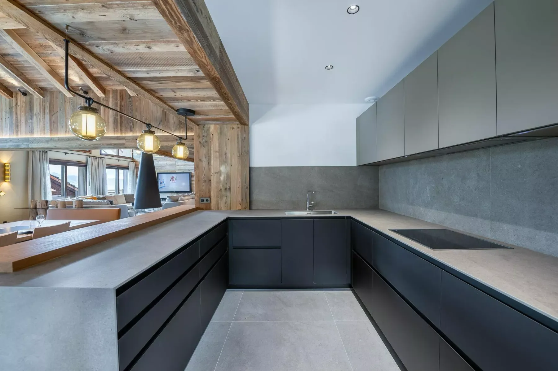 A modern kitchen with dark cabinets, gray countertops, and a large island.