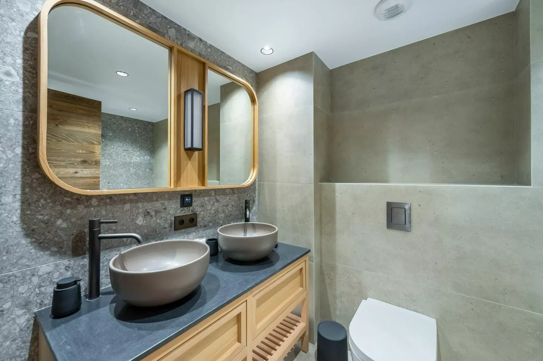 A modern bathroom with a double sink vanity, large mirror, and shower.