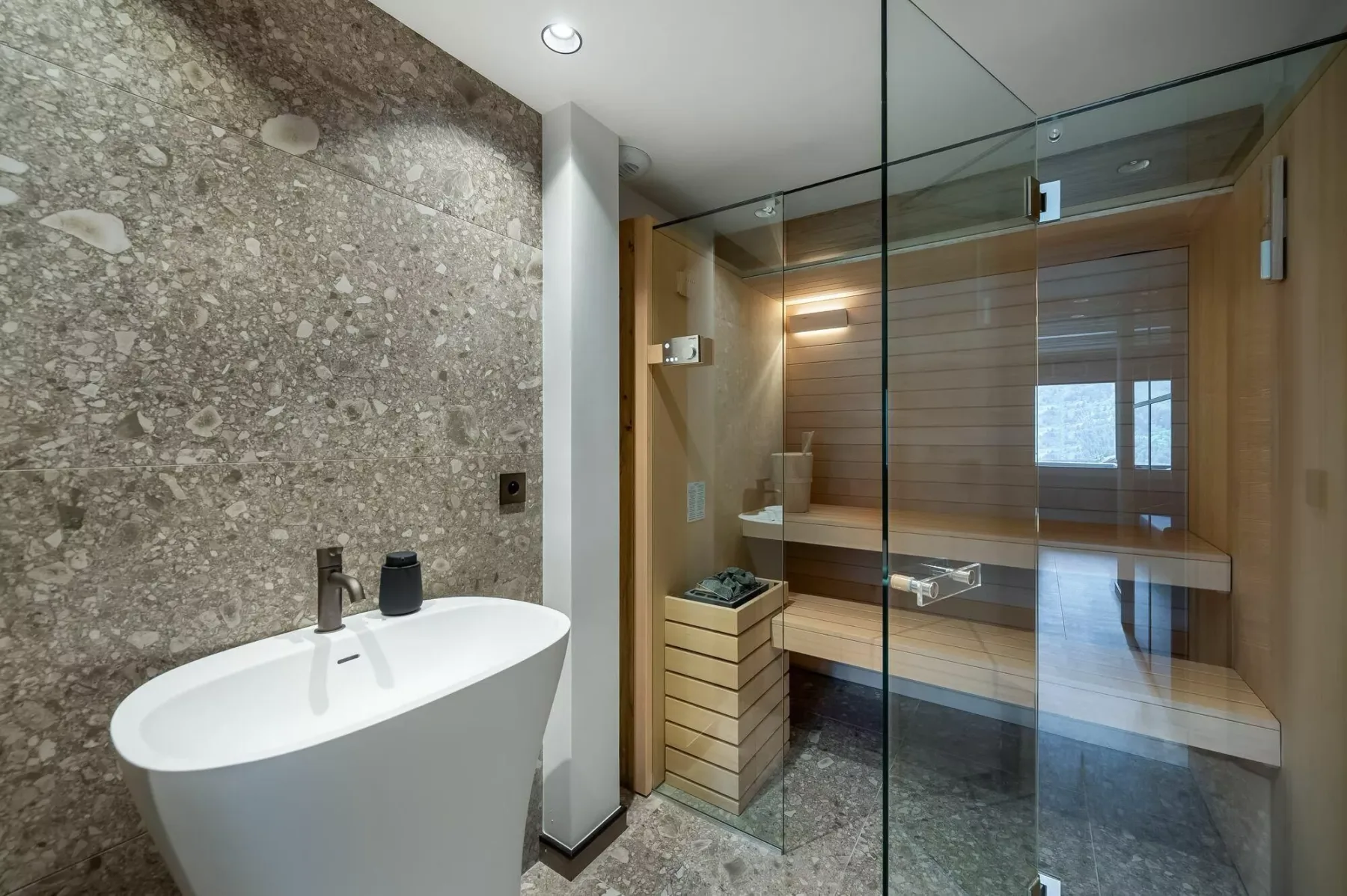 A modern bathroom with a freestanding tub and a glass-enclosed sauna.