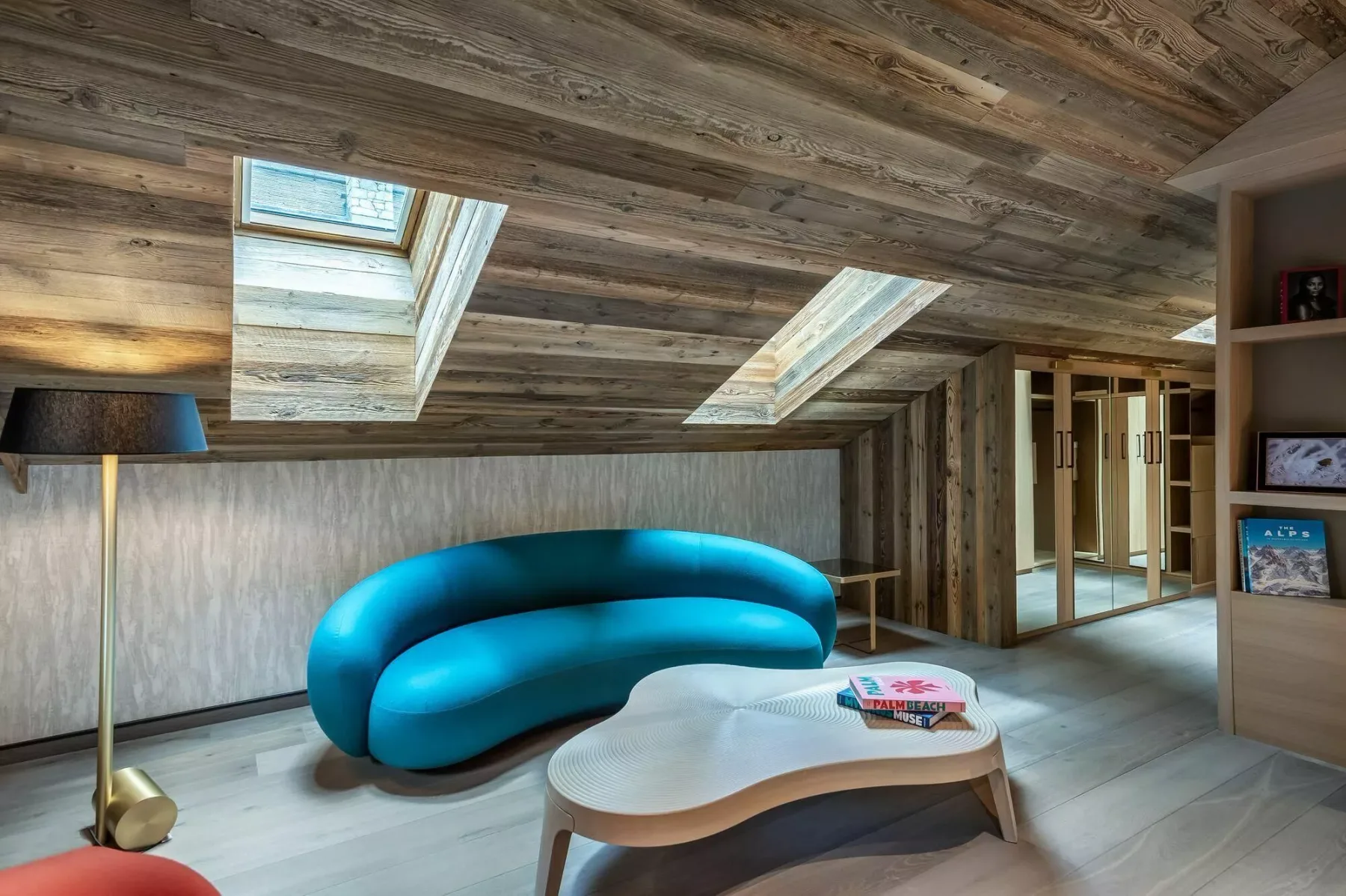 A modern lounge with bright blue seating and skylights in the sloped ceiling.