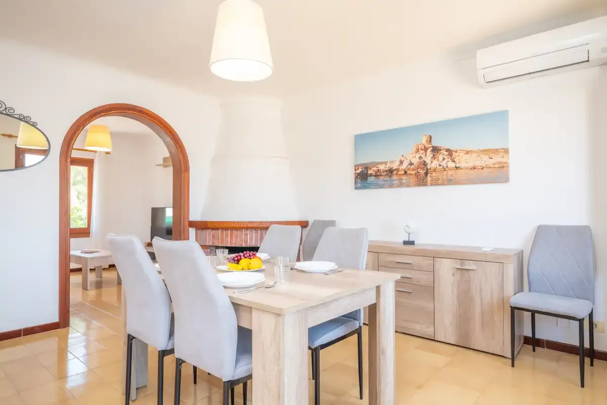 Comedor con una mesa, asientos tapizados y un aparador de madera.