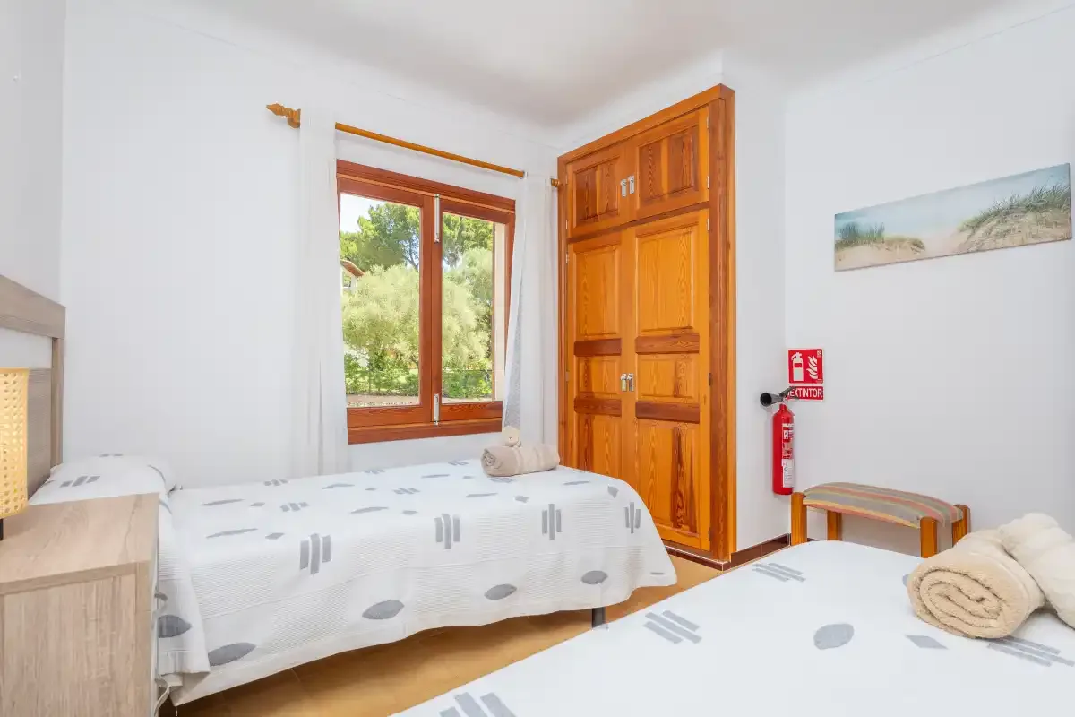 Un dormitorio con dos camas, una ventana y una puerta de madera.