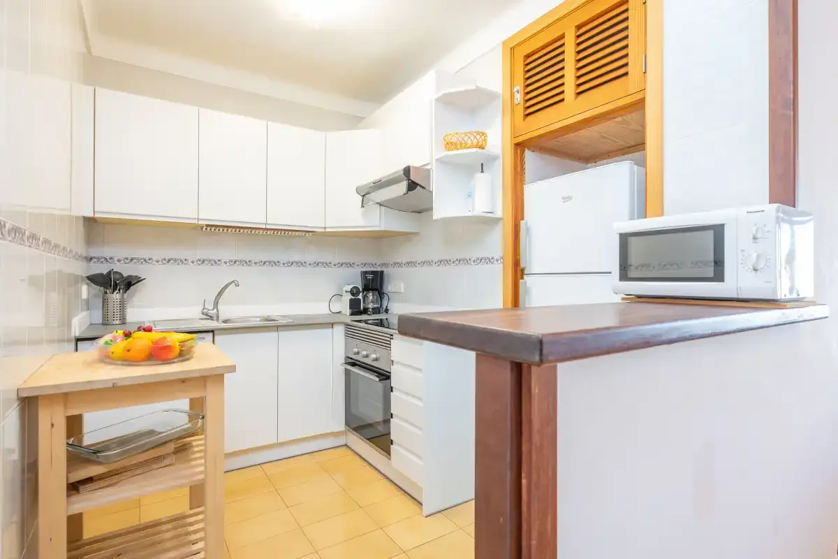 Una cocina luminosa con gabinetes blancos y una encimera.