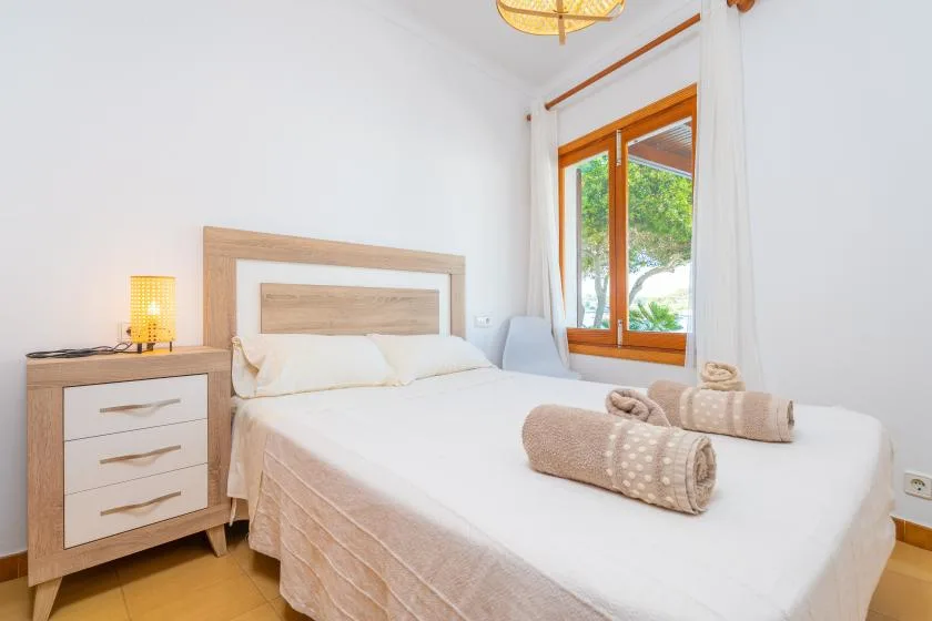 Un dormitorio luminoso con una cama doble y una ventana con marco de madera.