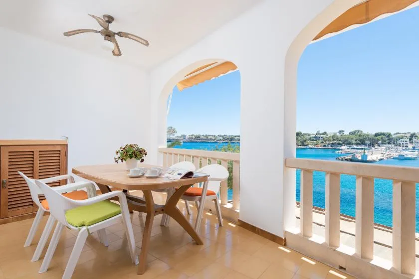 Un comedor se abre a un balcón con vistas al agua azul.