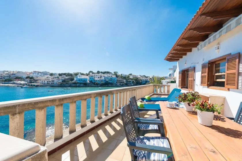 Una terraza soleada junto al mar, con asientos al aire libre y vistas al agua.