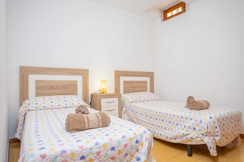 Un dormitorio luminoso con dos camas cubiertas de ropa de cama estampada y colorida.