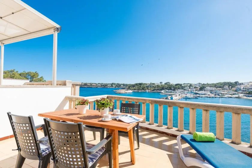 Una terraza junto al agua con asientos al aire libre y vistas a barcos.