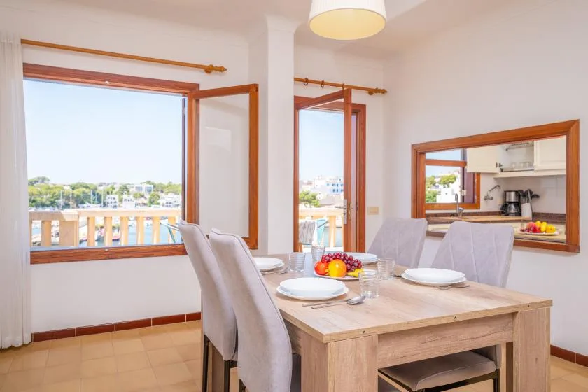 Comedor con la mesa puesta junto a grandes ventanas con vistas a un balcón.