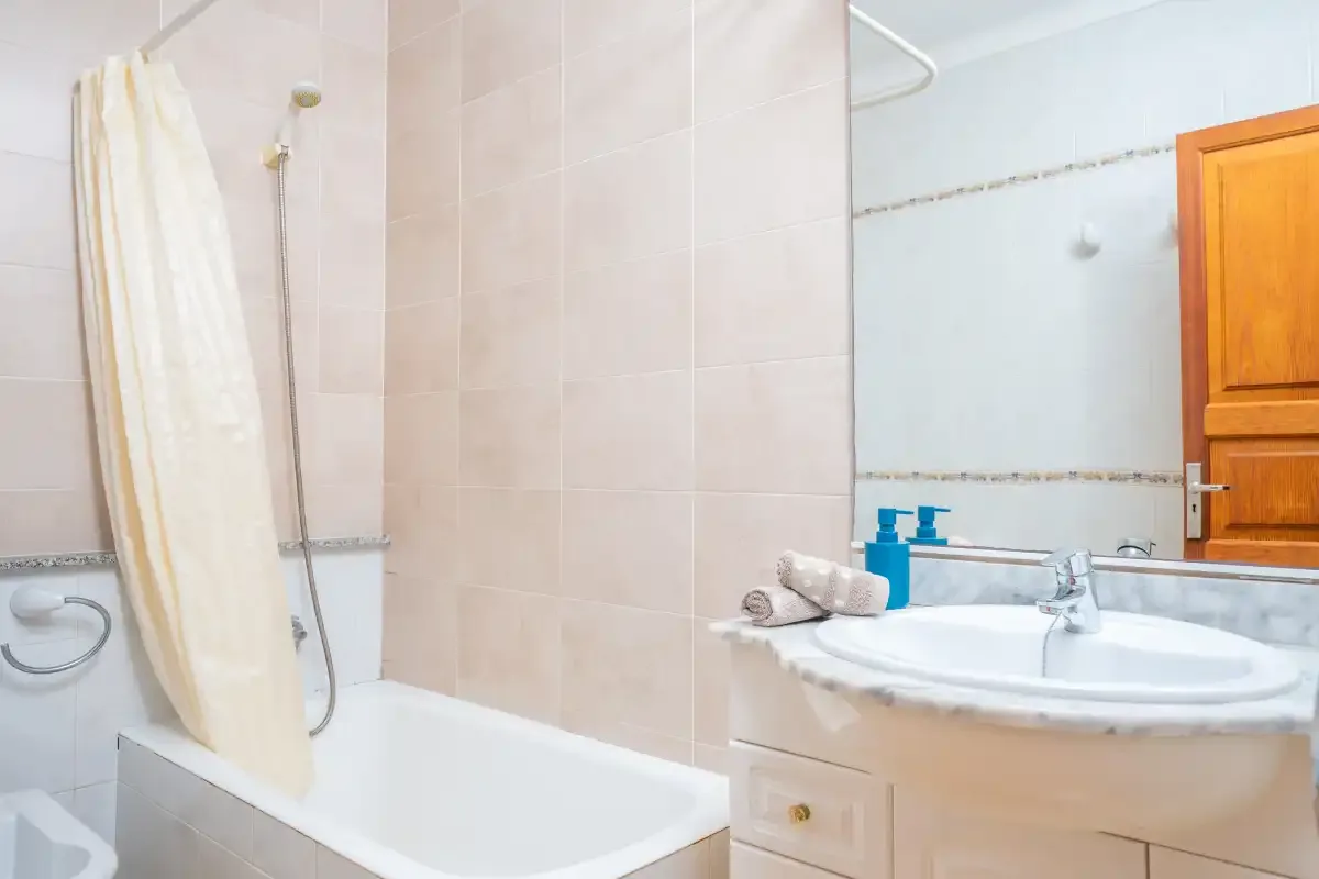 Un baño con bañera, cortina de ducha y lavabo.