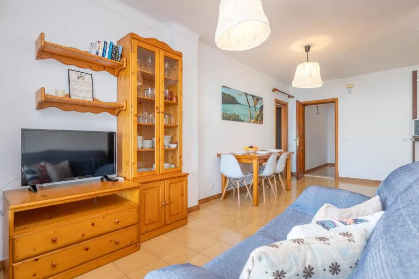 Una sala de estar con estanterías de madera, un televisor y una mesa de comedor.