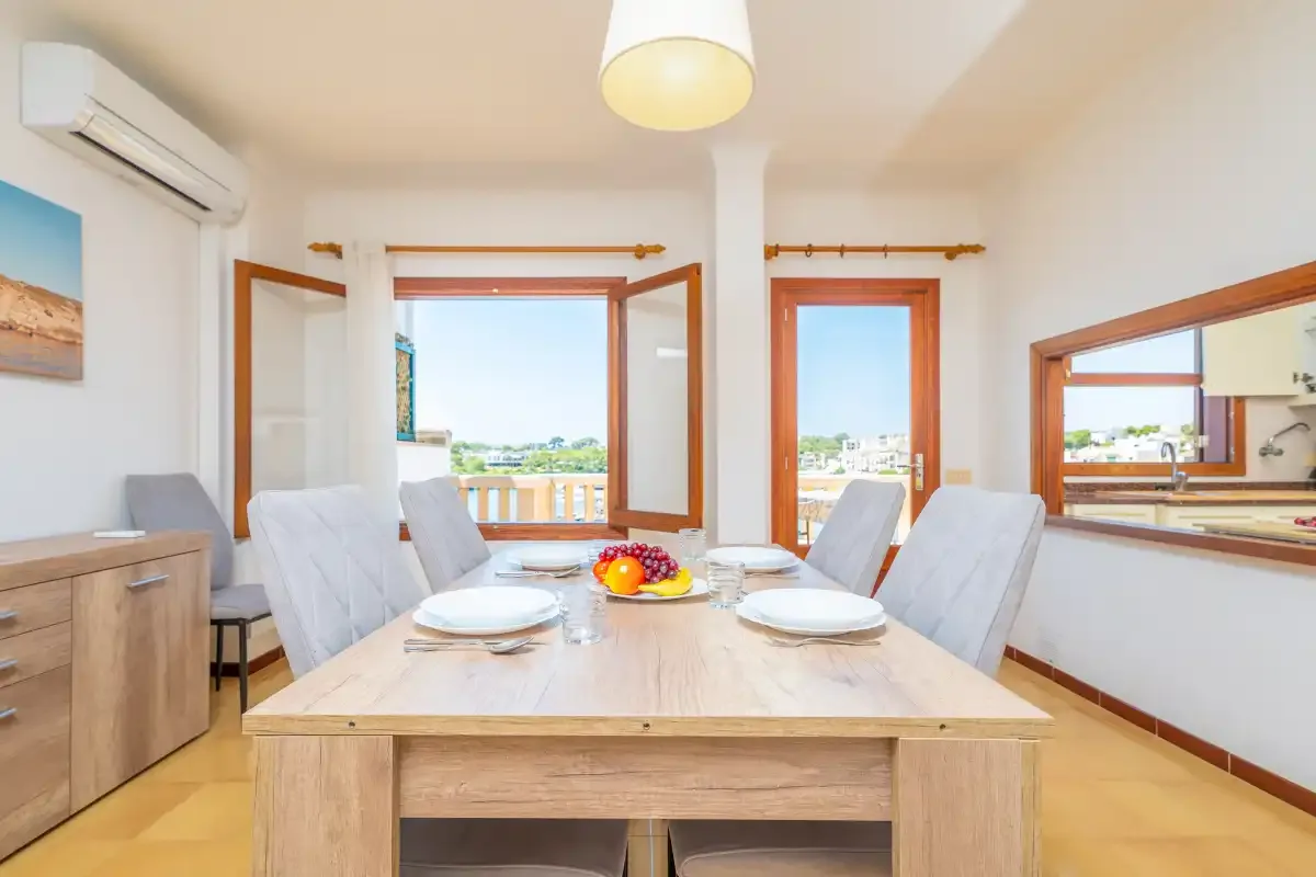 Comedor con una mesa puesta junto a ventanas con vistas al exterior.