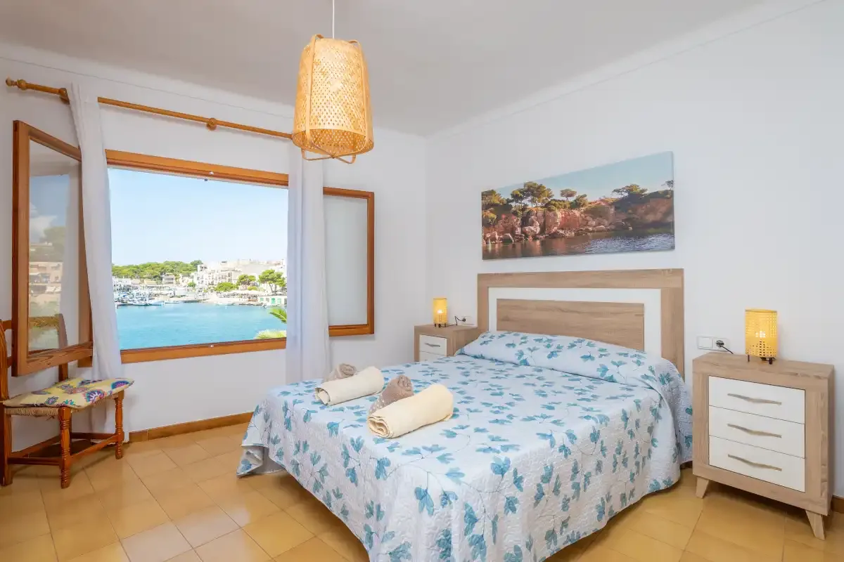 Un dormitorio luminoso con una cama doble y una ventana con vistas al agua.