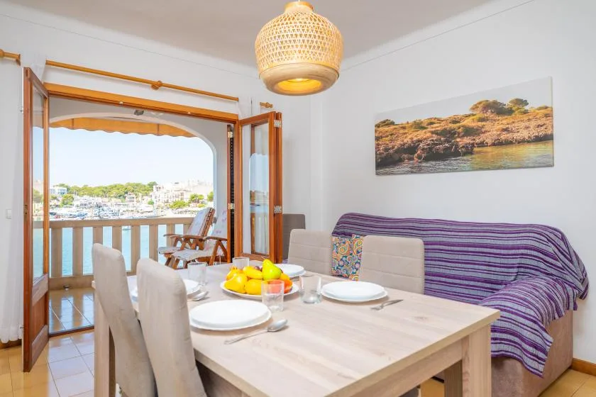 Comedor con la mesa puesta junto a puertas abiertas que dan a un balcón.