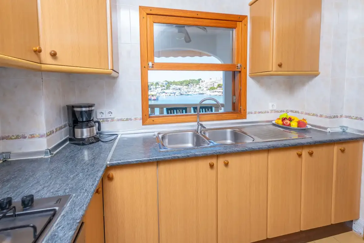 Una cocina con armarios de madera, un fregadero y una ventana con vistas al agua.