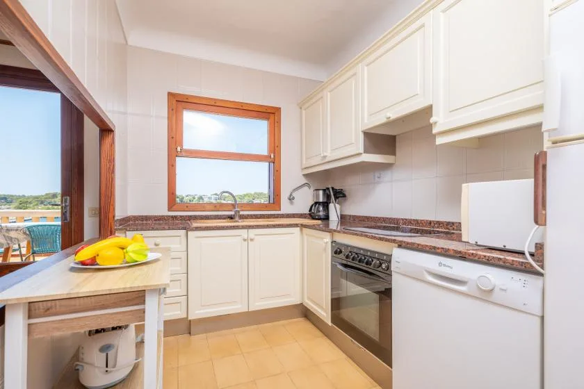 Una cocina luminosa con gabinetes blancos, encimera y electrodomésticos integrados.