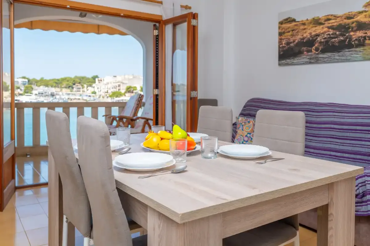 Comedor con la mesa puesta junto a puertas abiertas con vistas al agua.