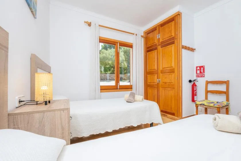 Un dormitorio luminoso con ropa de cama blanca, muebles de madera y una ventana.