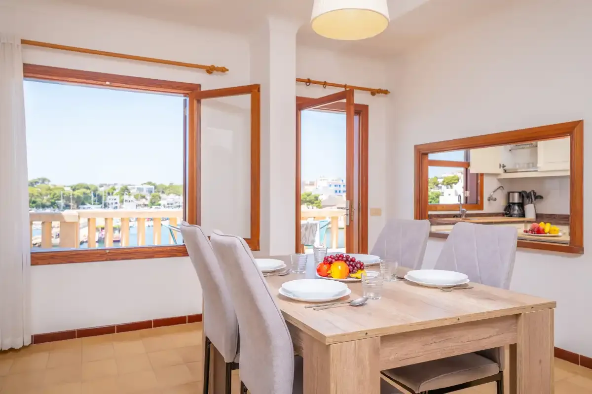 Comedor con una mesa de madera y vistas a través de ventanas abiertas.