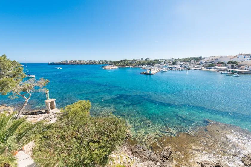 Una bahía costera de aguas azules y claras, costa rocosa y barcos cerca de la orilla.