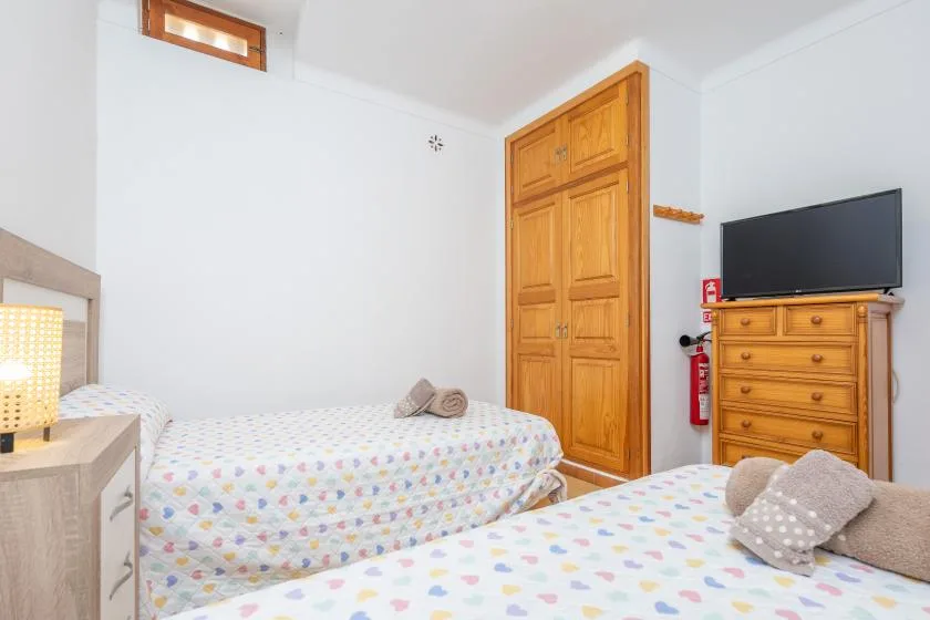 Un dormitorio con dos camas, una puerta de madera y un televisor sobre una cómoda.