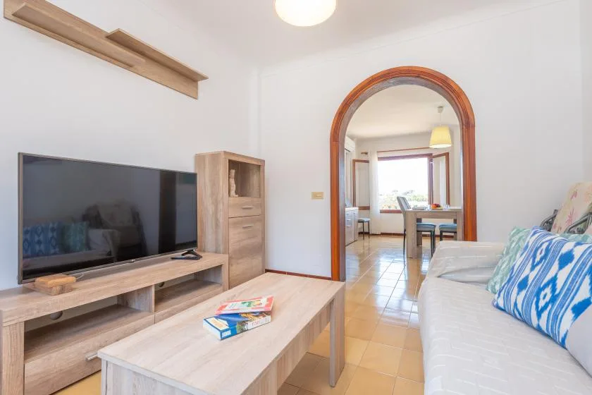 Una sala de estar con televisor, asientos y una mesa de centro de madera.