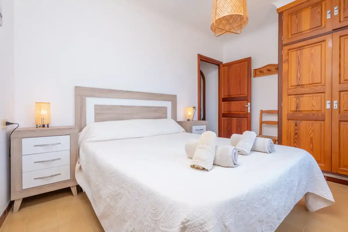 Un dormitorio con una cama bien arreglada y armarios de madera.