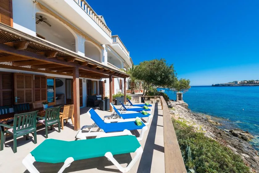 Una terraza junto al mar con asientos de descanso mira hacia el agua azul.
