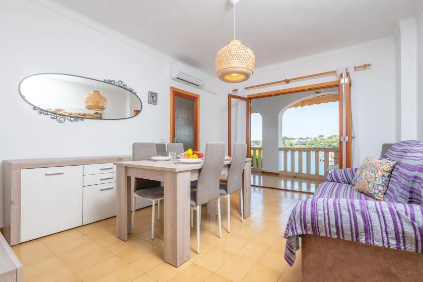 Un luminoso comedor y sala de estar con una mesa, asientos y una puerta abierta al balcón.