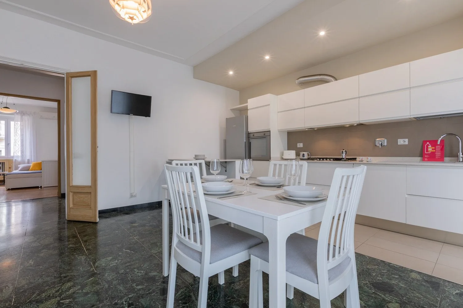 Un comedor con la mesa puesta está junto a una cocina moderna.
