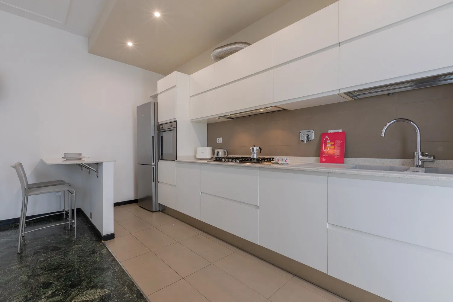 Una cocina moderna con gabinetes blancos, una encimera y un fregadero.