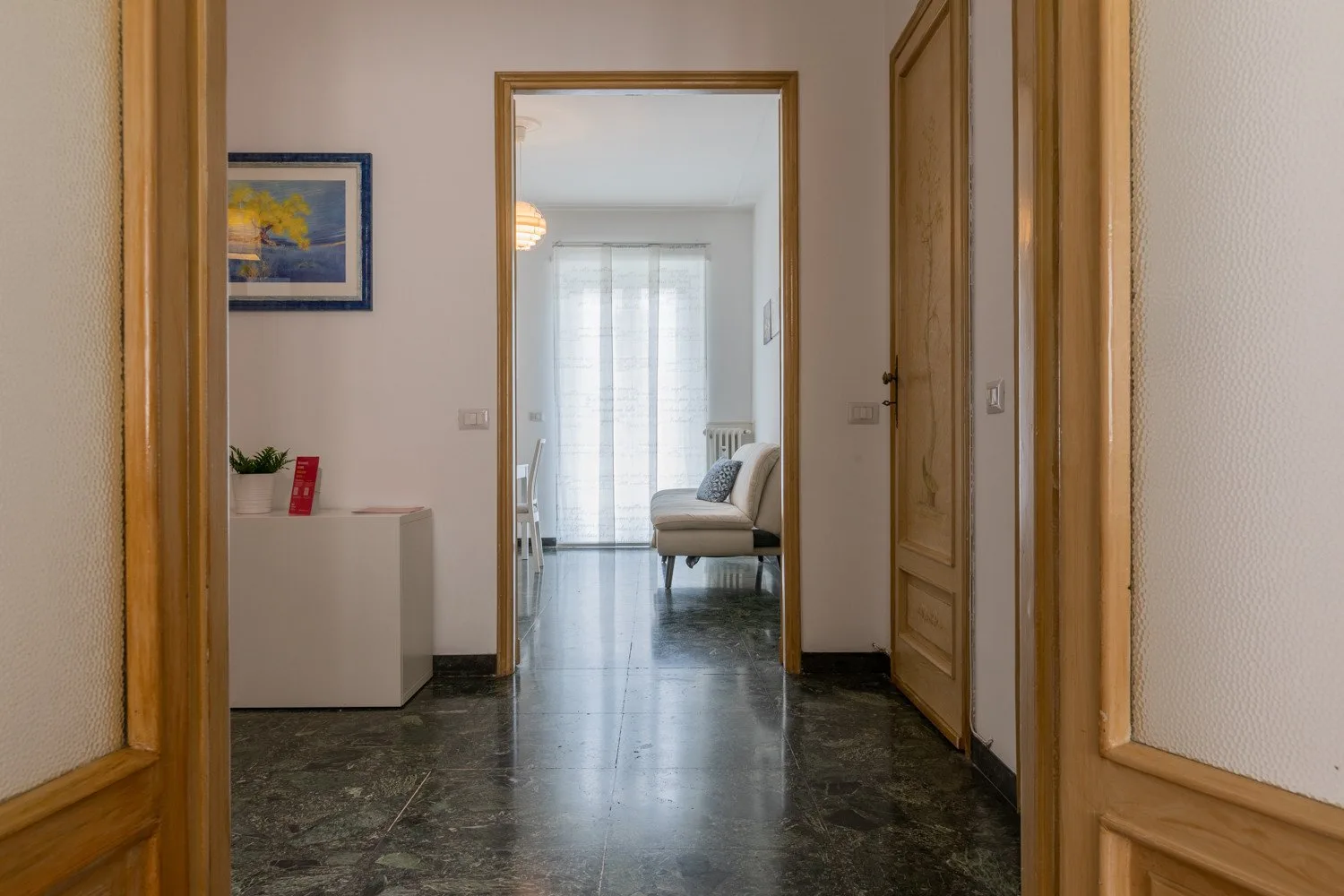 Un pasillo da a una luminosa zona de estar con una ventana al fondo.