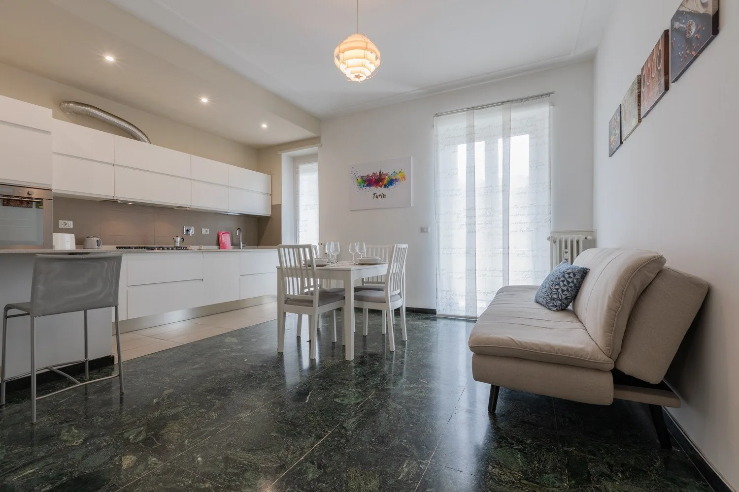 Una luminosa cocina abierta con comedor y asientos junto a una ventana grande.