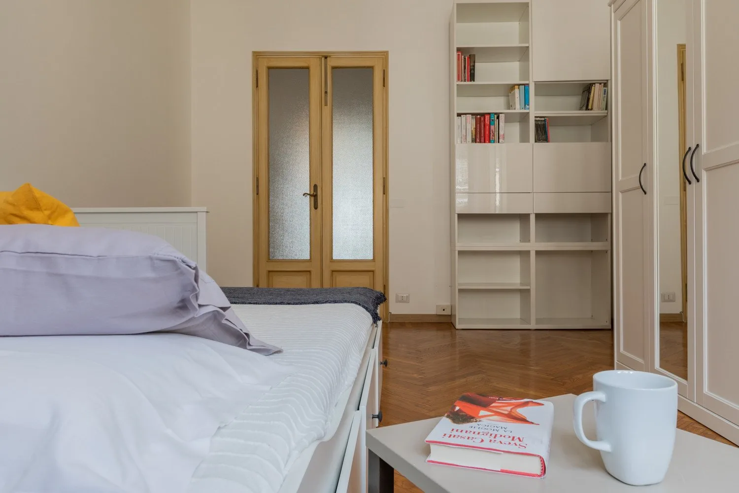 Un dormitorio con una cama, estanterías empotradas y una mesa pequeña.