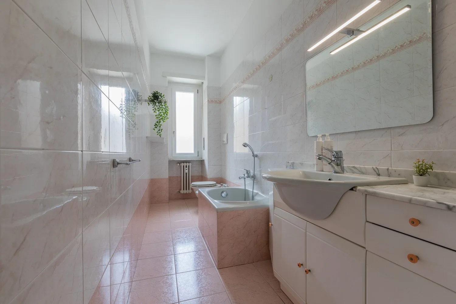 Un baño revestido de azulejos con bañera, lavabo y un gran espejo.
