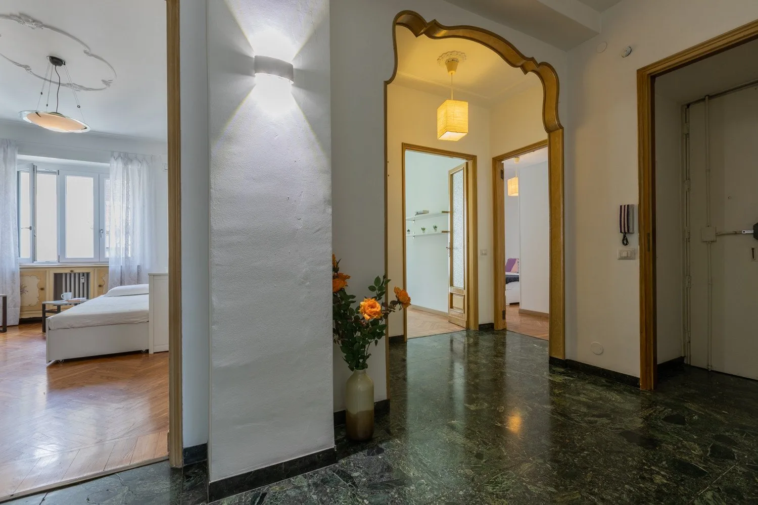 Un pasillo con un arco se abre hacia un dormitorio luminoso.