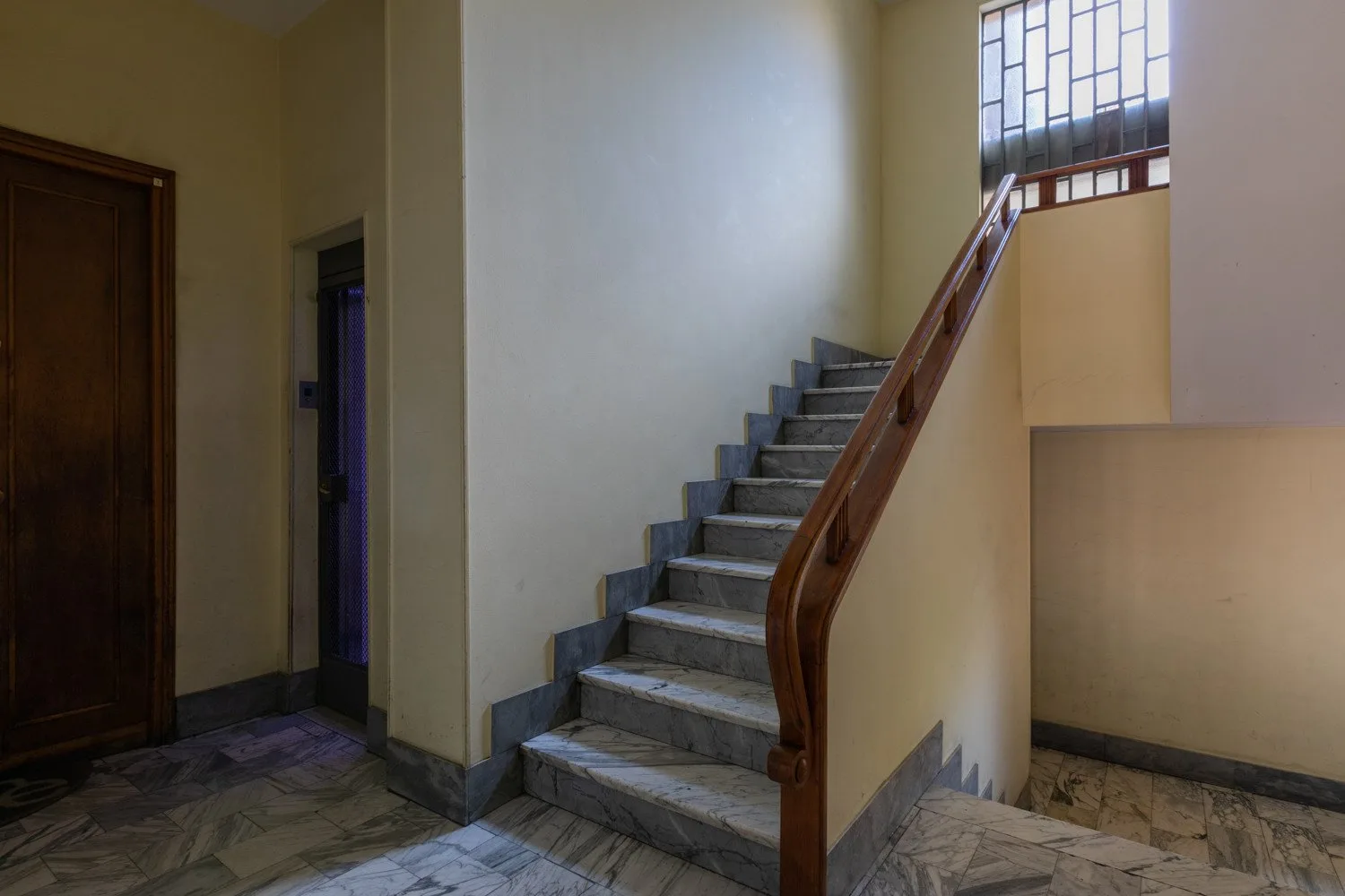Una escalera interior con peldaños de piedra y pasamanos de madera.