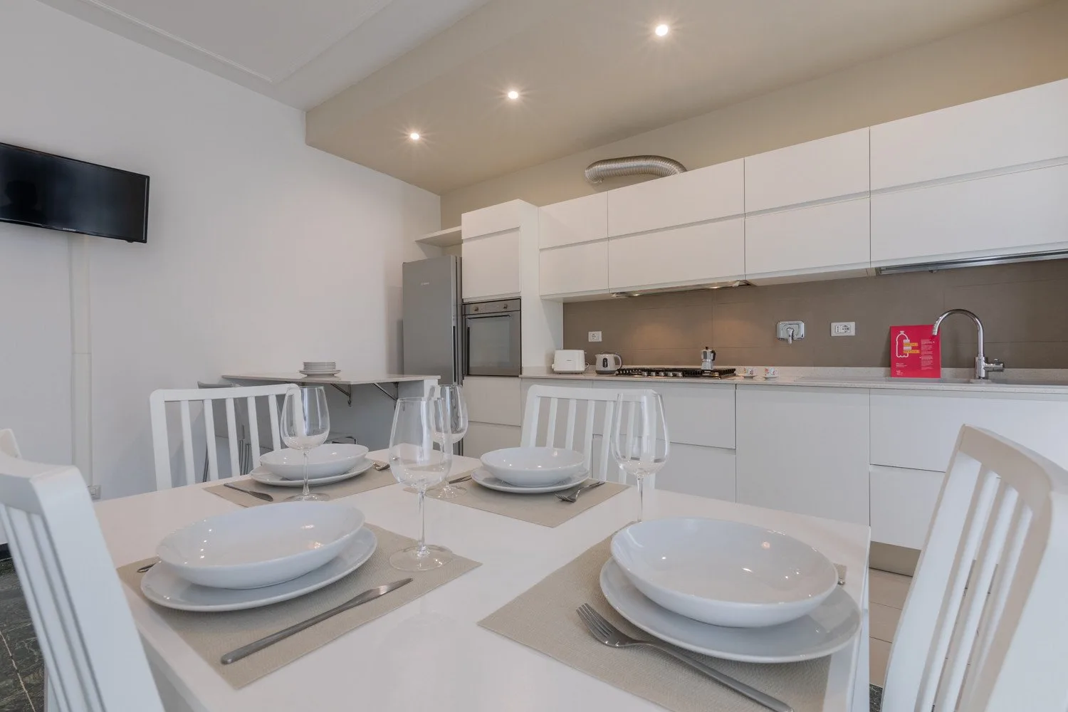 Un comedor luminoso con la mesa puesta junto a una cocina moderna.