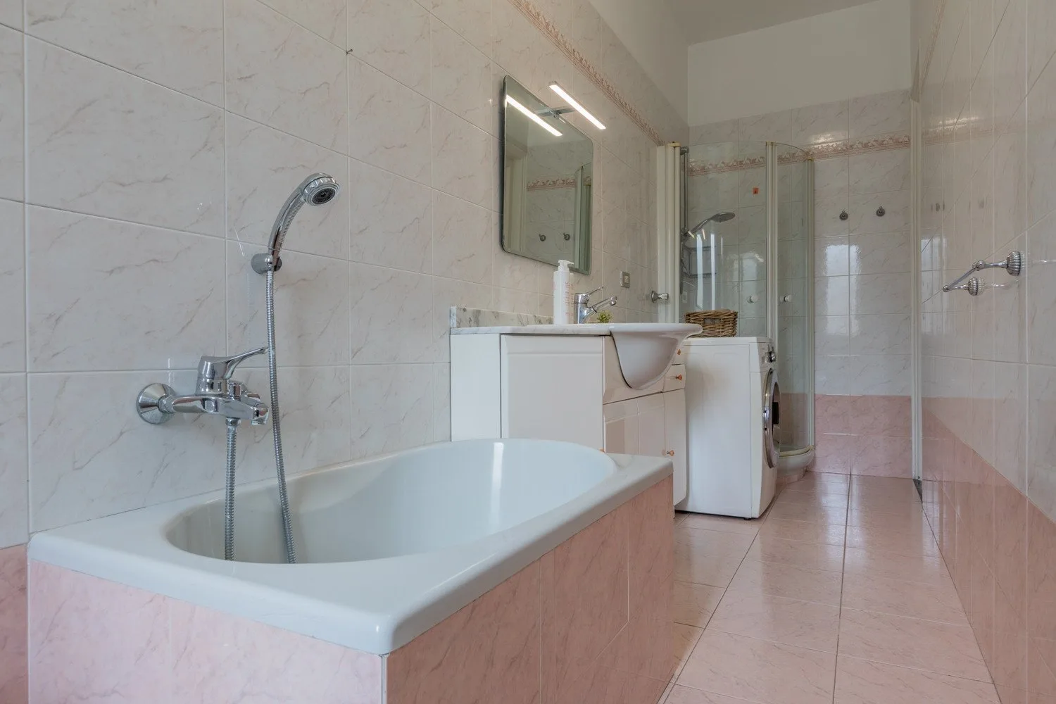 Un baño alicatado con bañera, lavabo y mampara de ducha de vidrio.
