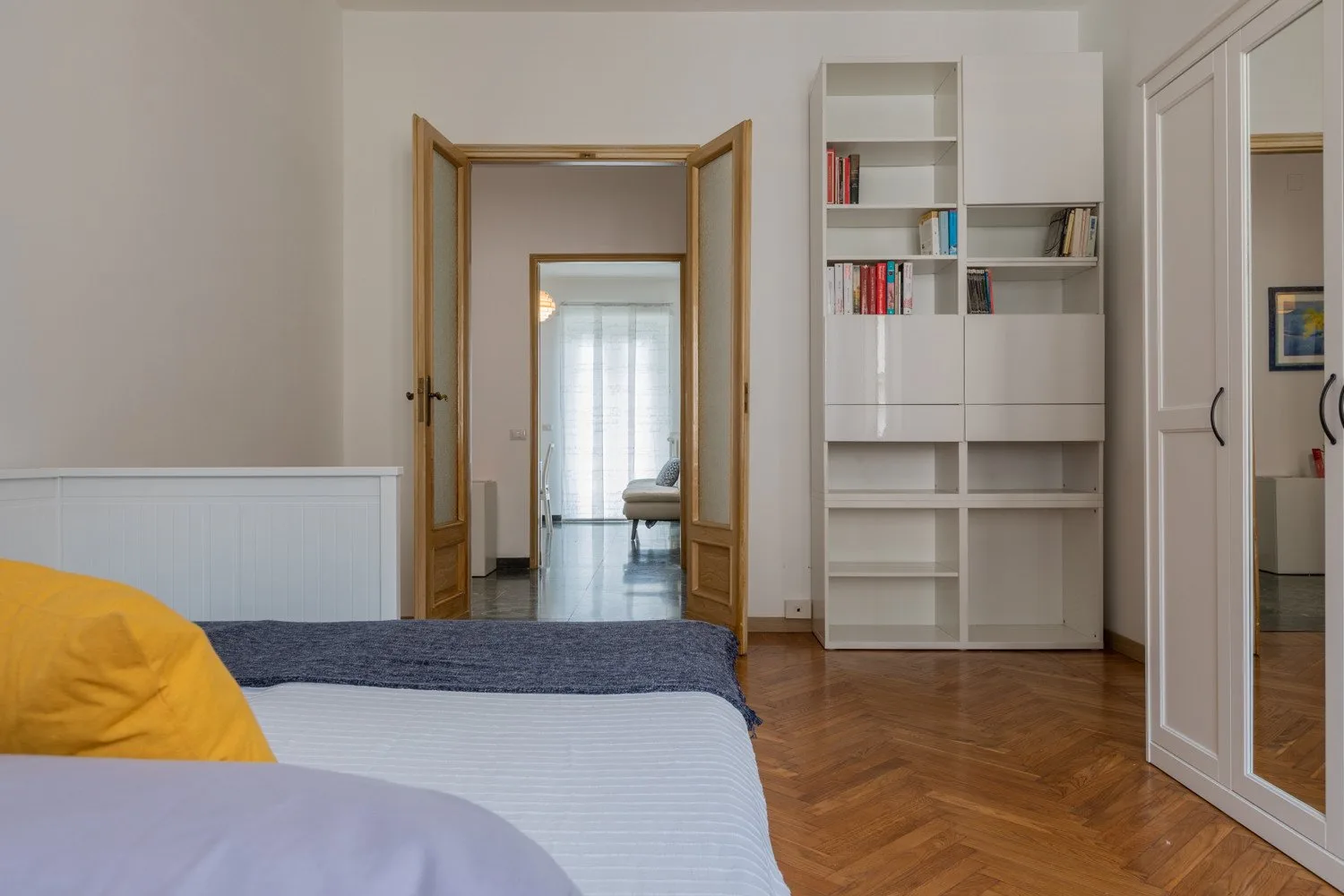 Un dormitorio con una cama, estanterías empotradas y una puerta abierta.