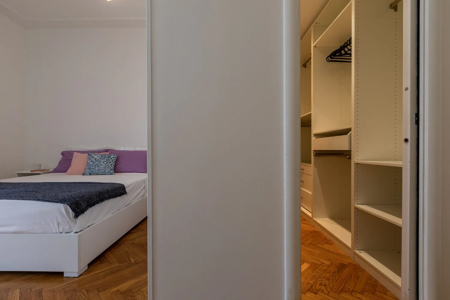 Un dormitorio con una cama junto a un armario empotrado abierto.
