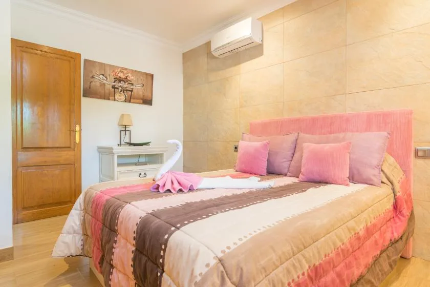 Un dormitorio con una cama bien tendida y un aire acondicionado en la pared.
